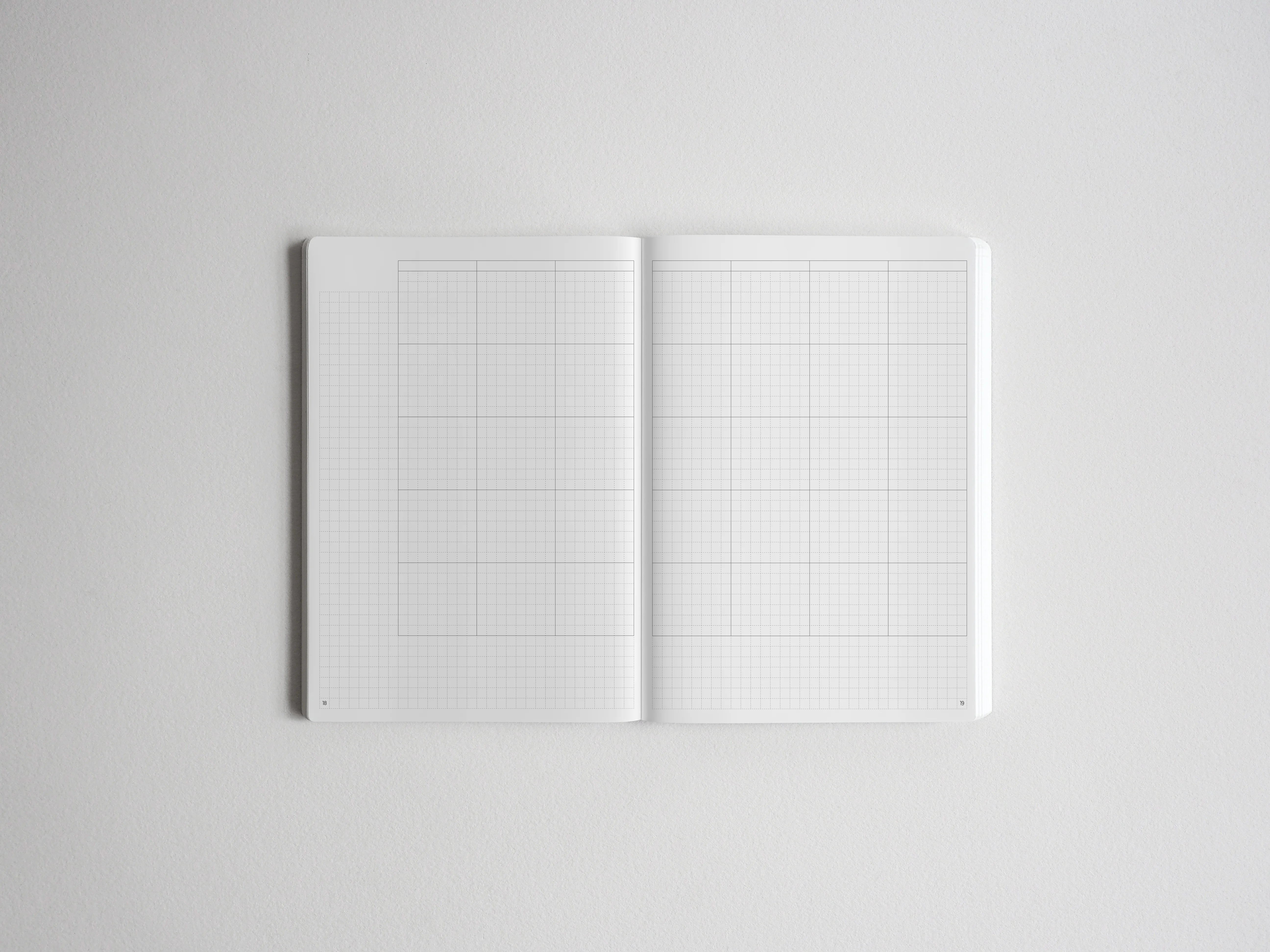 Open notebook spread showing two pristine white pages printed with fine graph paper grids, perfect for sketching, planning, or journaling.