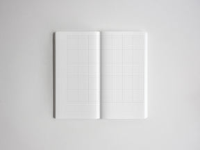 Open spiral planner notebook displaying a crisp, light gray graph paper grid, ideal for technical drawing, detailed note-taking, or bullet journaling.