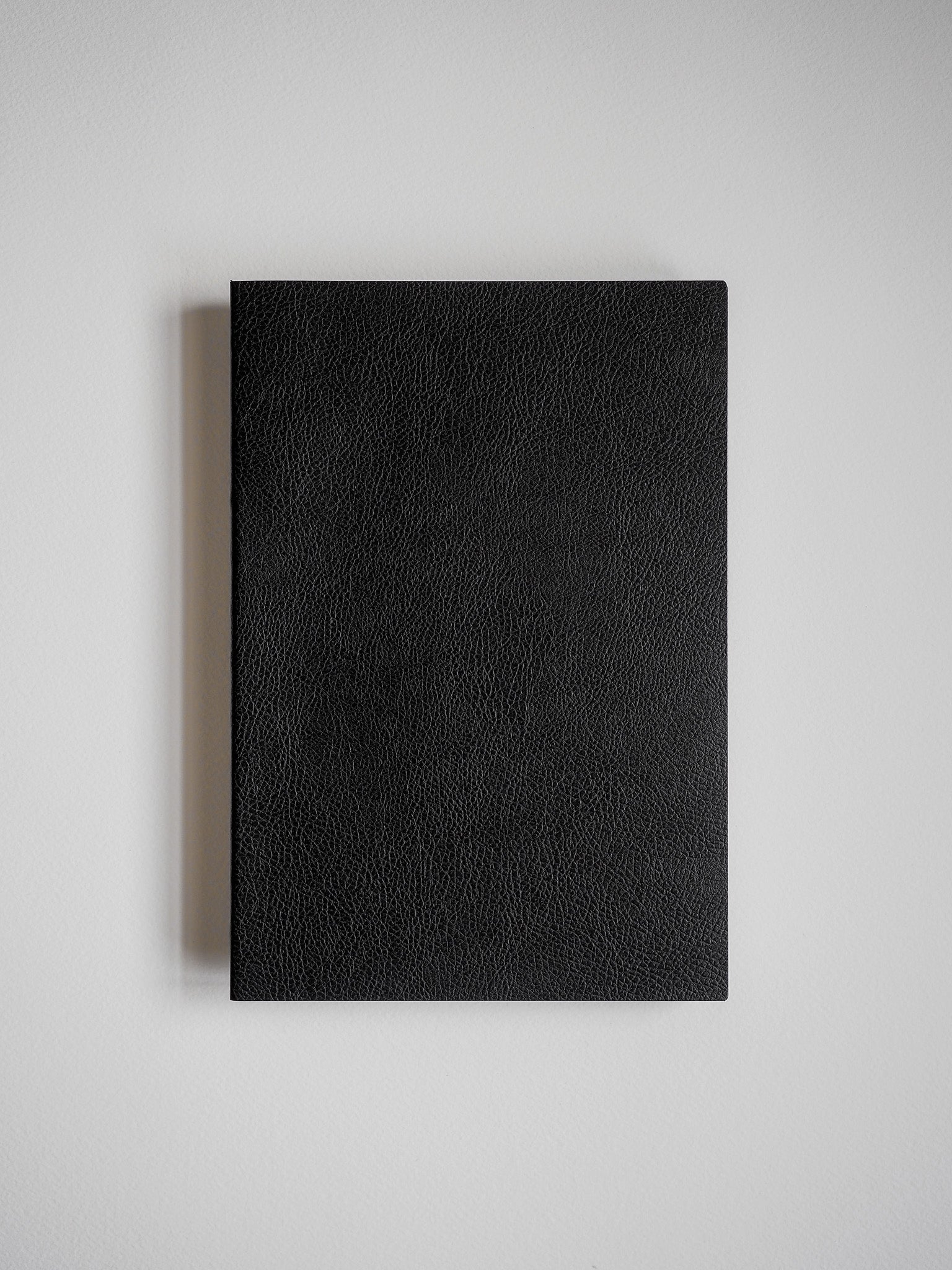 Deep black, textured faux-leather cover of an A5 lined notebook, perfect for journal entries or professional note-taking.