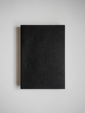 Deep black, textured faux-leather cover of an A5 lined notebook, perfect for journal entries or professional note-taking.