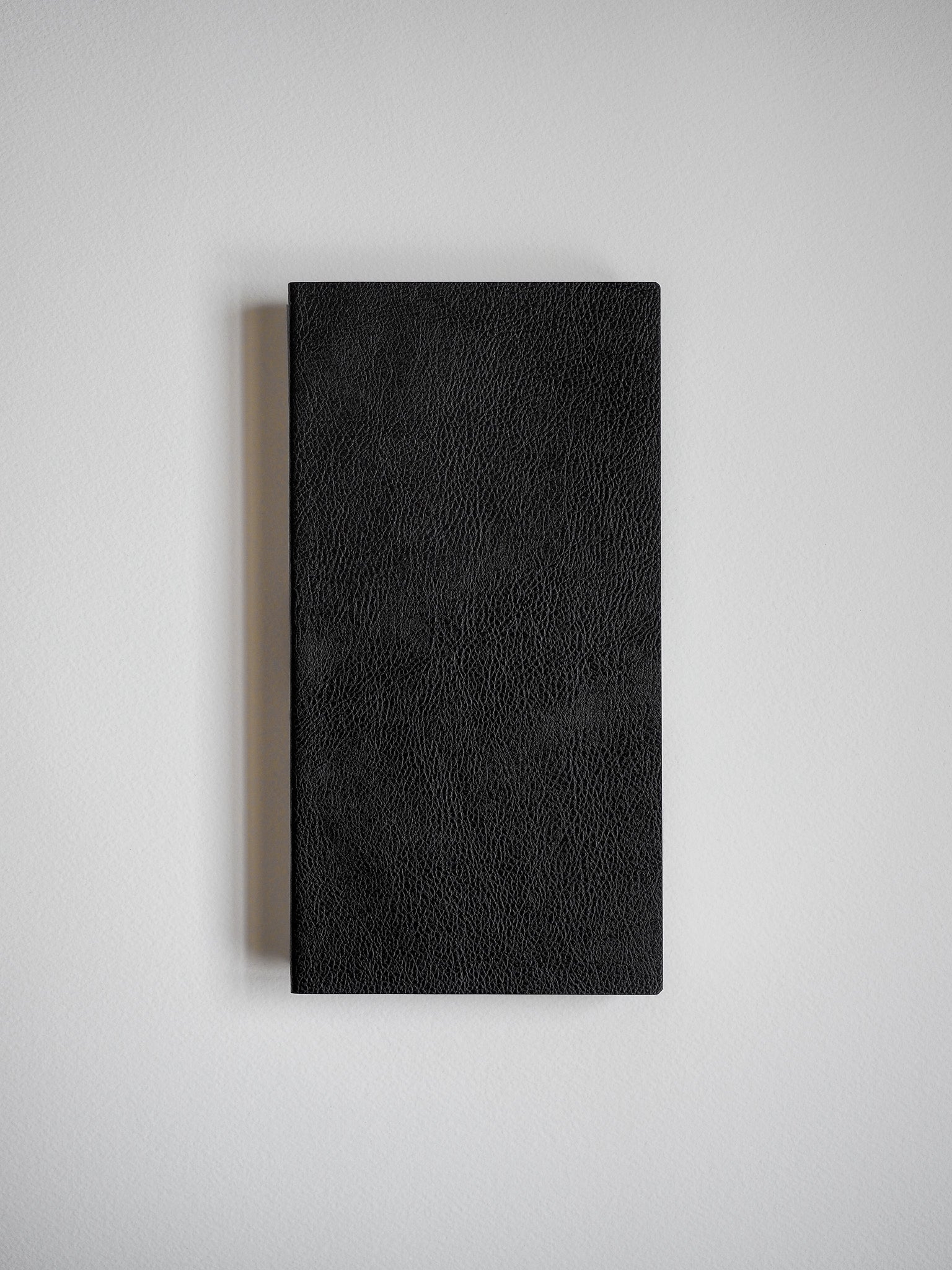 Closed, black notebook with a subtly pebbled texture, designed for writing and journaling.