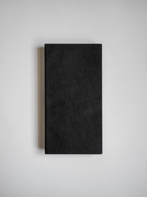 Closed, black notebook with a subtly pebbled texture, designed for writing and journaling.