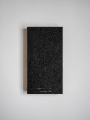 Sleek, black faux-leather notebook with a textured finish and elegant gold embossing, designed for writing and note-taking.