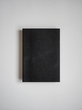 Solid black notebook featuring a textured, minimalist faux leather cover, designed for writing, journaling, or work notes.