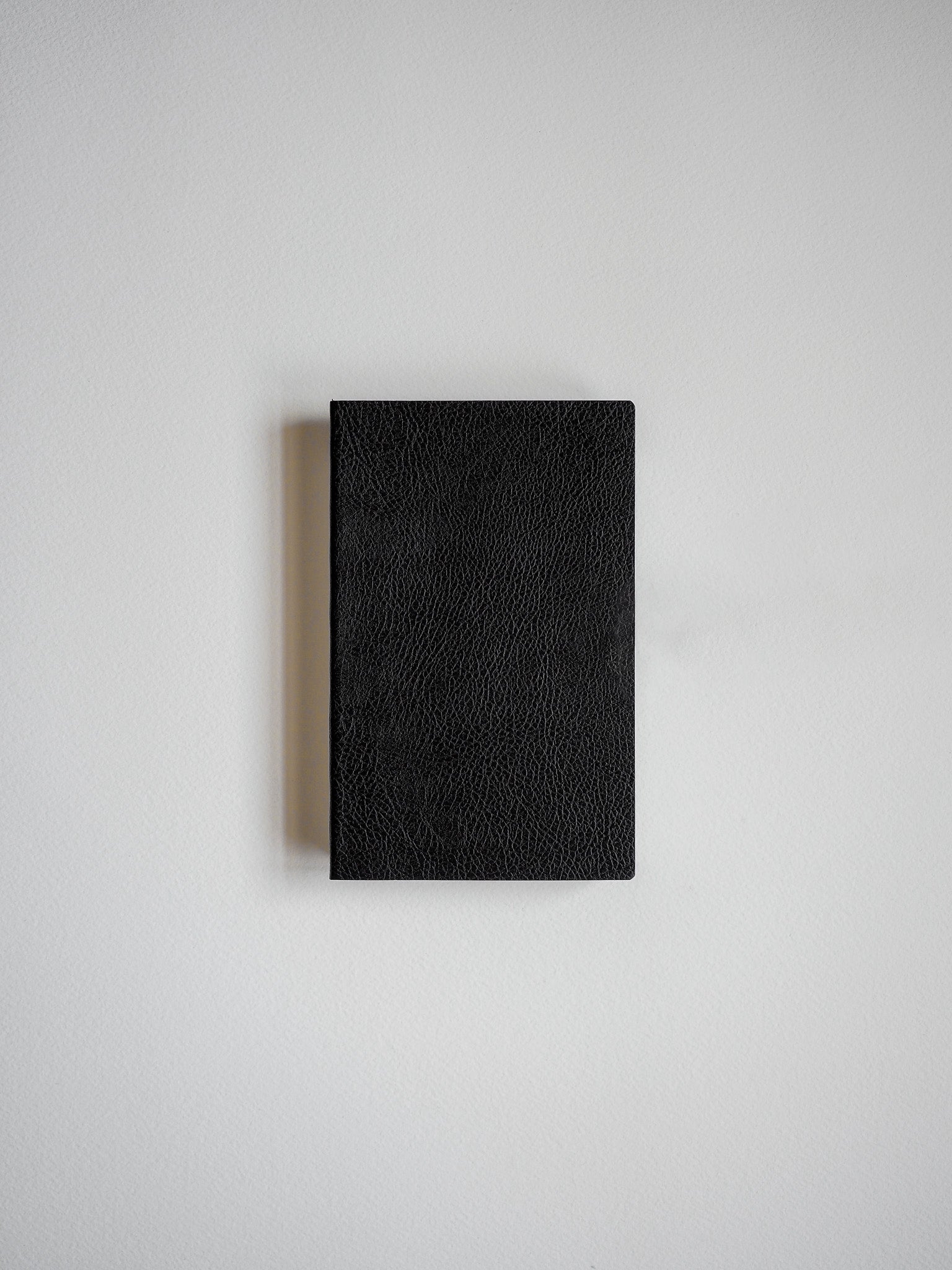 Solid black pocket notebook featuring a richly textured, faux-leather cover for writing and journaling.