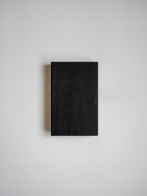 Solid black pocket notebook featuring a richly textured, faux-leather cover for writing and journaling.