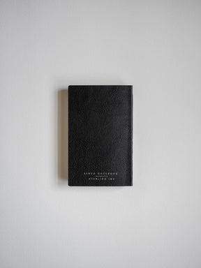 Black, pocket-sized lined notebook with a textured cover, featuring prominent gold-colored embossed lettering for "LINED NOTEBOOK" by Sterling Ink.