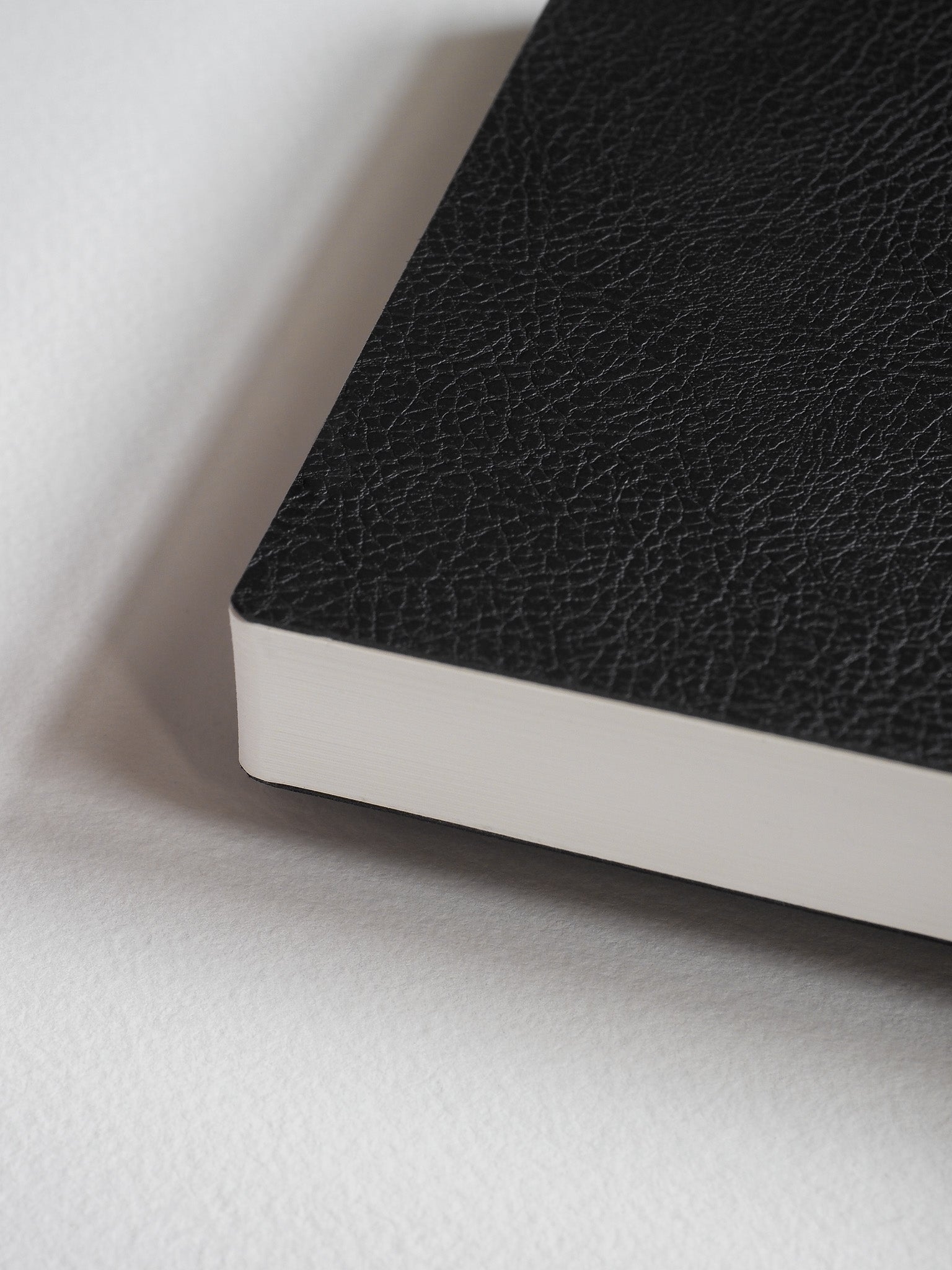 Portable pocket notebook featuring a textured, matte black faux-leather cover and clean white edges suitable for daily note-taking.