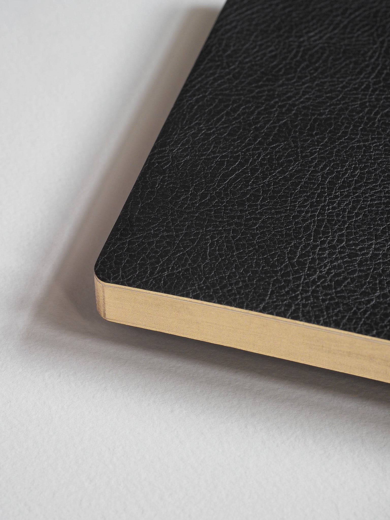 Structured A5 notebook bound in light tan, featuring a sophisticated black cover with a refined, textured finish perfect for writing and journaling.