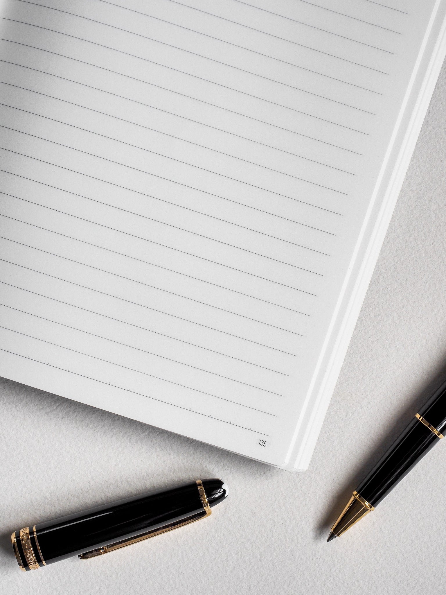 Plain white notebook open to a page with ruled lines and visible page numbering, designed for organized writing and note-taking.