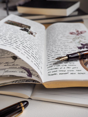 Open B6 ruled notebook displaying creamy, lined pages with faint printed headers, ideal for journaling and academic note-taking.