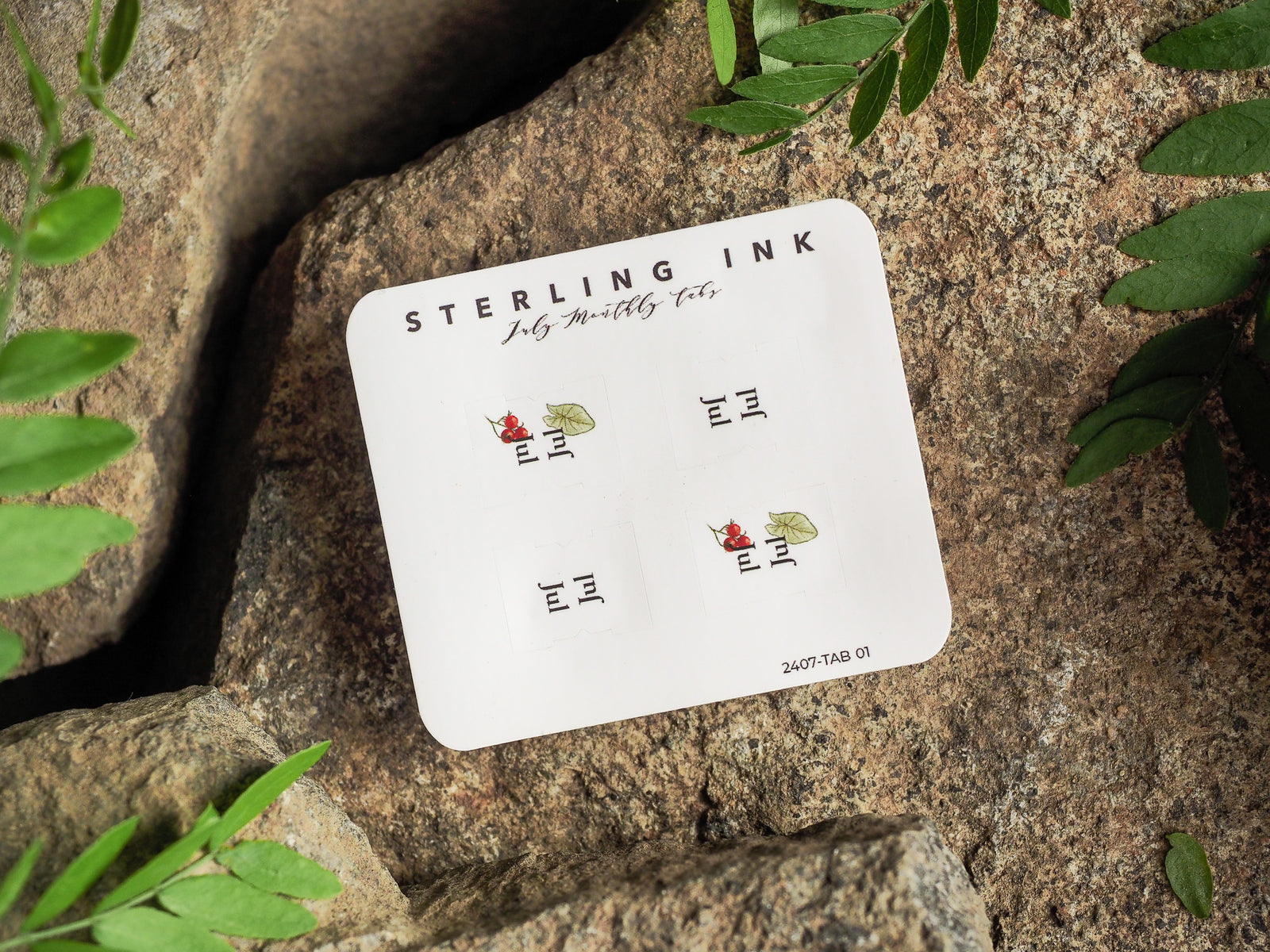 White planner tab set for July 2024, featuring neatly labeled dates and accented with small, charming red and green foliage designs for a seasonal touch.