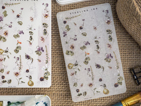 Delicate botanical washi strip stickers featuring detailed watercolor florals, berries, and green foliage on contrasting cream and dusty gray backgrounds.
