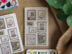 Vintage picture frame stickers featuring sepia-toned designs of rustic homes, floral arrangements, and quaint scenes perfect for scrapbooking or journaling.