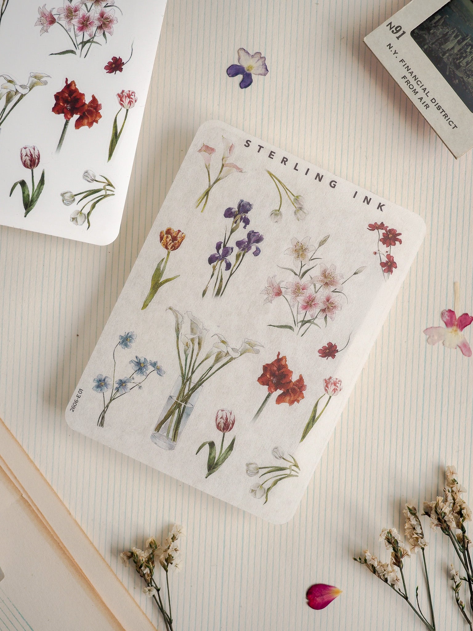 Elegant botanical pattern notepad featuring a detailed watercolor illustration of wildflowers, including lilies, tulips, and irises, printed with the title 'STERLING INK'.