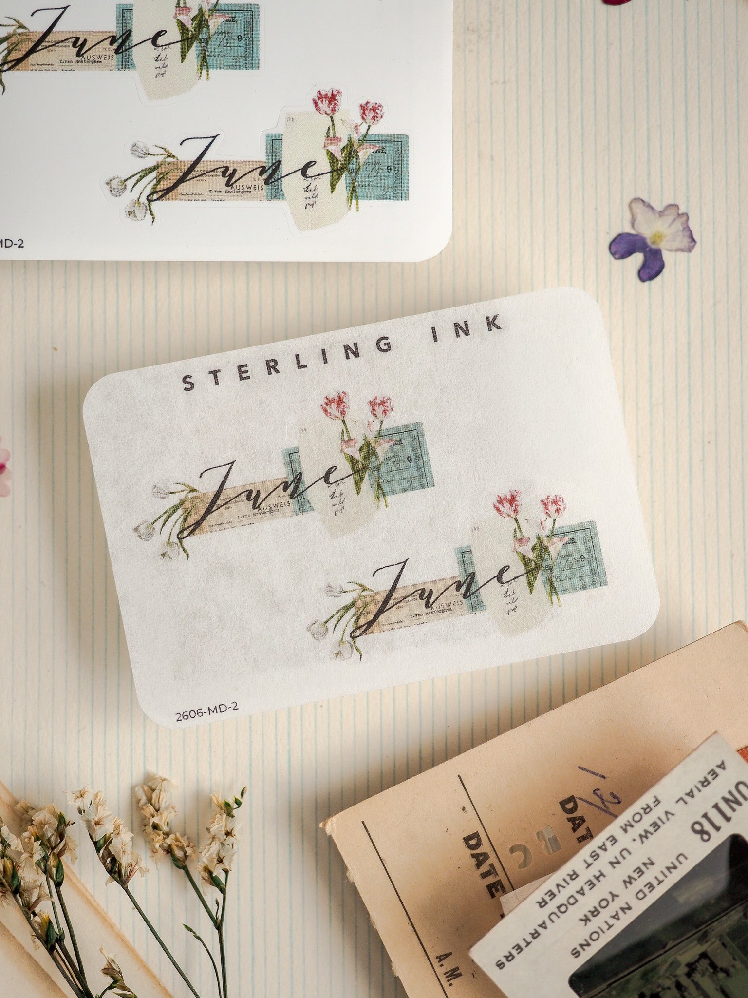 Cream-colored stationery printed with "STERLING INK," featuring elegant handwritten "June" script and delicate watercolor floral sprigs in pink and green tones.