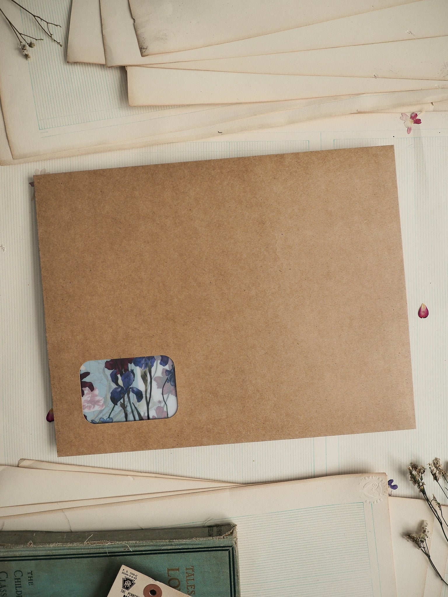 Rustic kraft cardstock featuring a small, delicate watercolor sticker design with soft blue and pink floral blossoms for crafting.