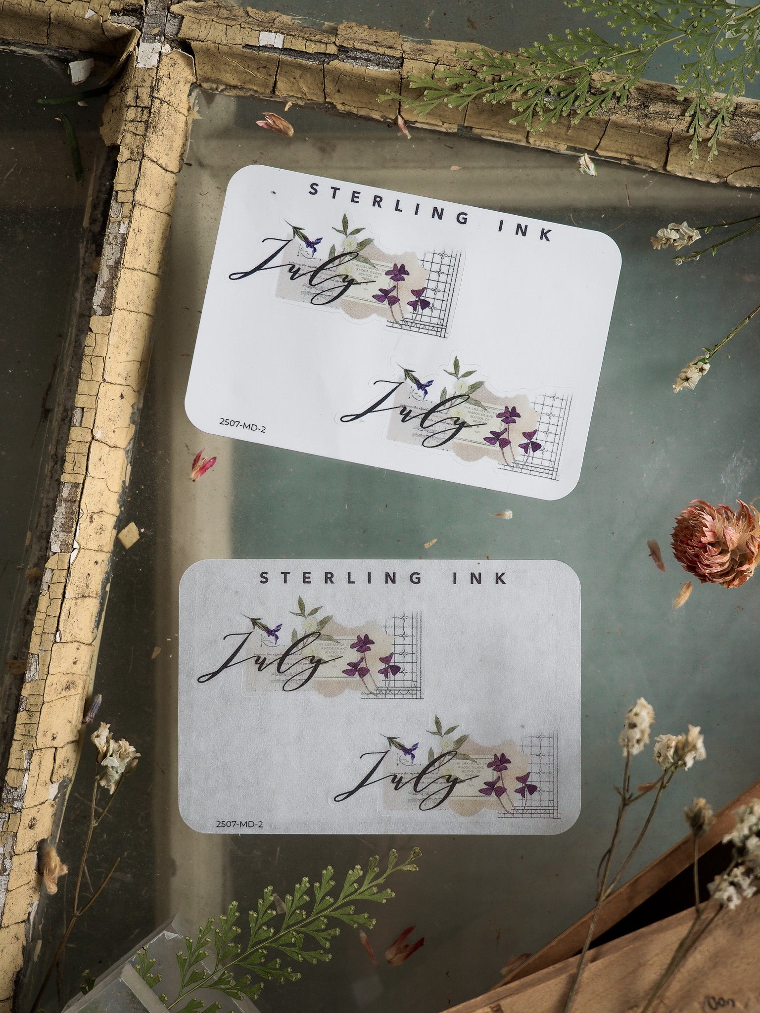 Elegant month sticker set for July, featuring the word "July" in sweeping cursive calligraphy adorned with purple floral accents and geometric designs.