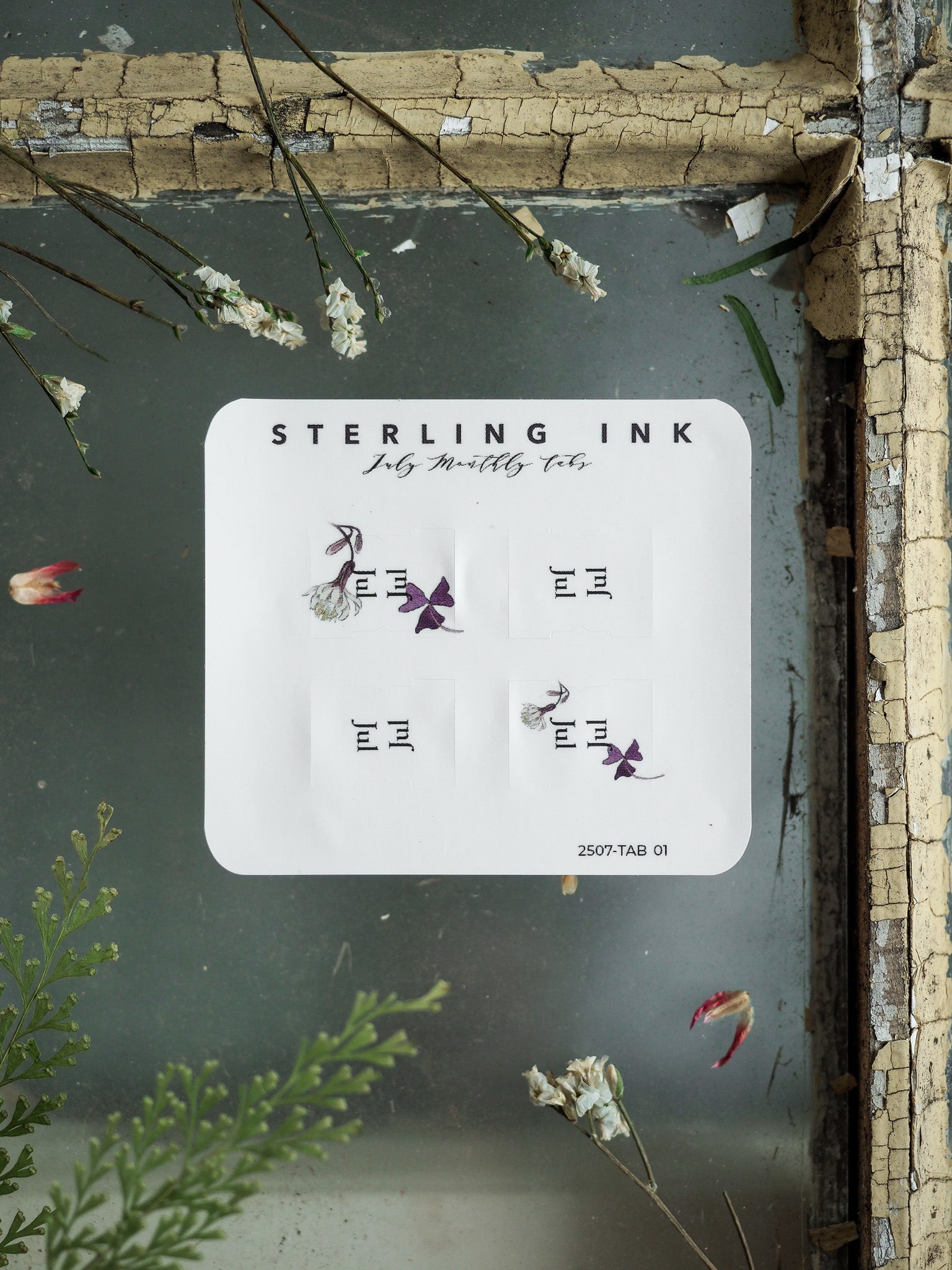 Set of printable monthly planner tabs on white cardstock, featuring the "Sterling Ink" logo and six decorative icons, including graceful purple butterflies and simple geometric dividers.