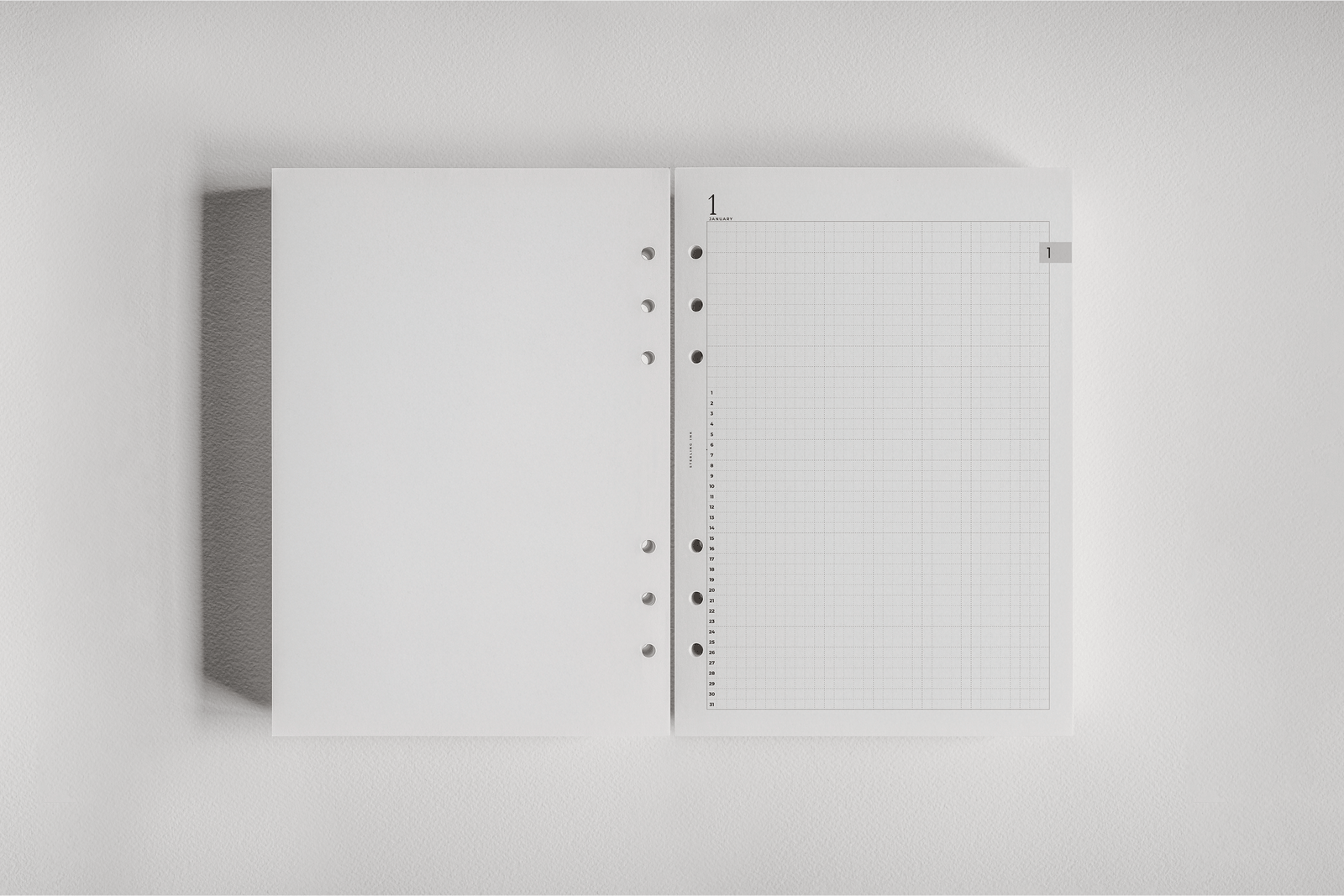 White spiral-bound daily planner insert featuring a smooth blank page adjacent to a detailed, structured graph grid layout for organized 2026 tracking.