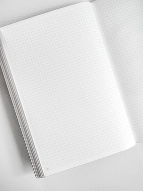 Open A5 graph paper notebook booklet featuring neatly gridded white pages, ideal for technical drawing, journaling, or structured note-taking.