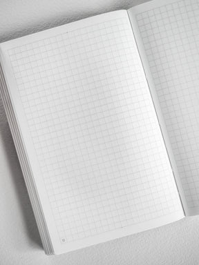 Open pocket monthly booklet displaying crisp, light-colored gridded graph paper pages, perfect for structured planning and journaling.