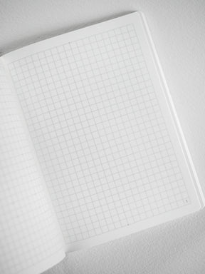 Minimalist notebook booklet displaying pale, structured grid graph paper perfect for organized journaling, plotting, or precise sketching.