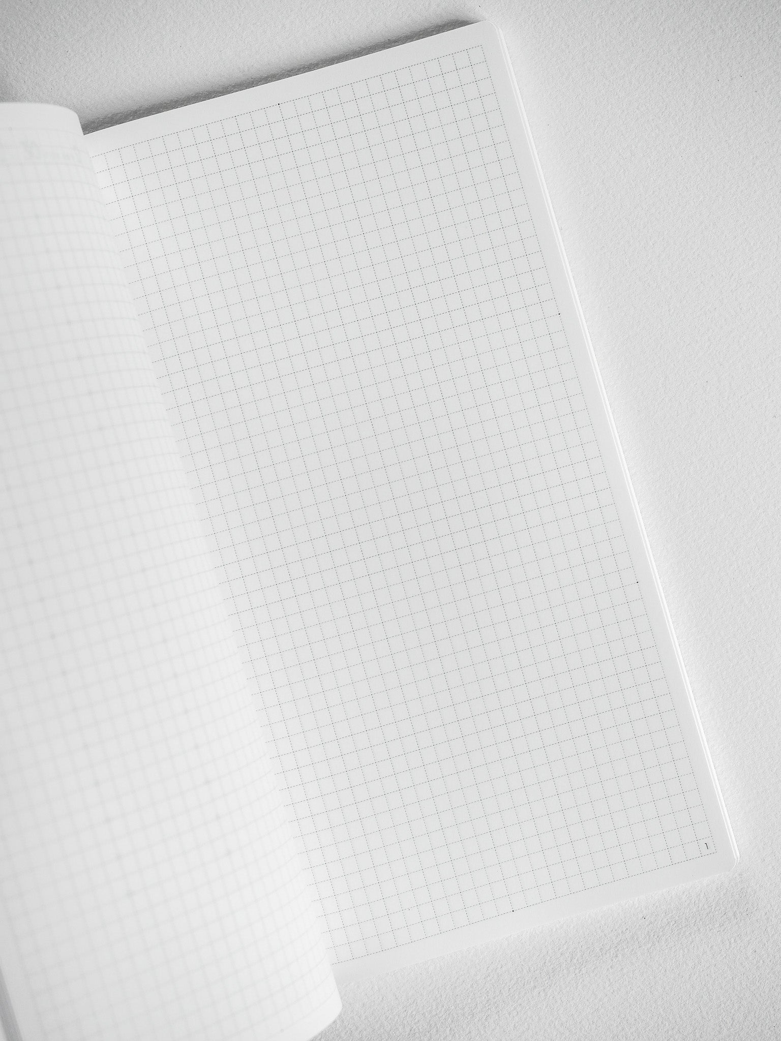 White notebook booklet with open graph paper pages, featuring precise grid lines perfect for technical drawing, journaling, and studying.