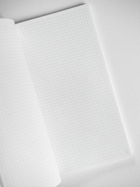 White notebook booklet with open graph paper pages, featuring precise grid lines perfect for technical drawing, journaling, and studying.