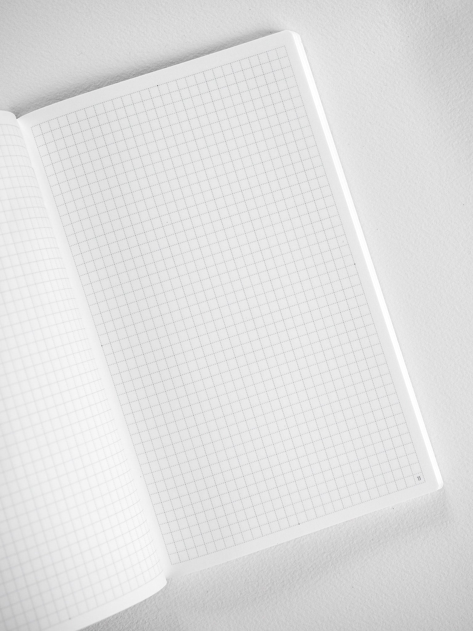 Open, white B6 booklet displaying a fine, uniformly gridded pattern, perfect for detailed monthly planning and structured note-taking.