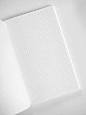Open, white B6 booklet displaying a fine, uniformly gridded pattern, perfect for detailed monthly planning and structured note-taking.