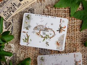 Elegant corner sticker sheet (August 2023) featuring intricate silver foil accents and a seasonal botanical arrangement of white flowers, delicate leaves, and rustic natural elements.