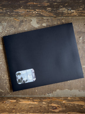 Matte black stationary piece featuring a subtle corner decal with delicate, faded botanical illustrations and natural green accents.
