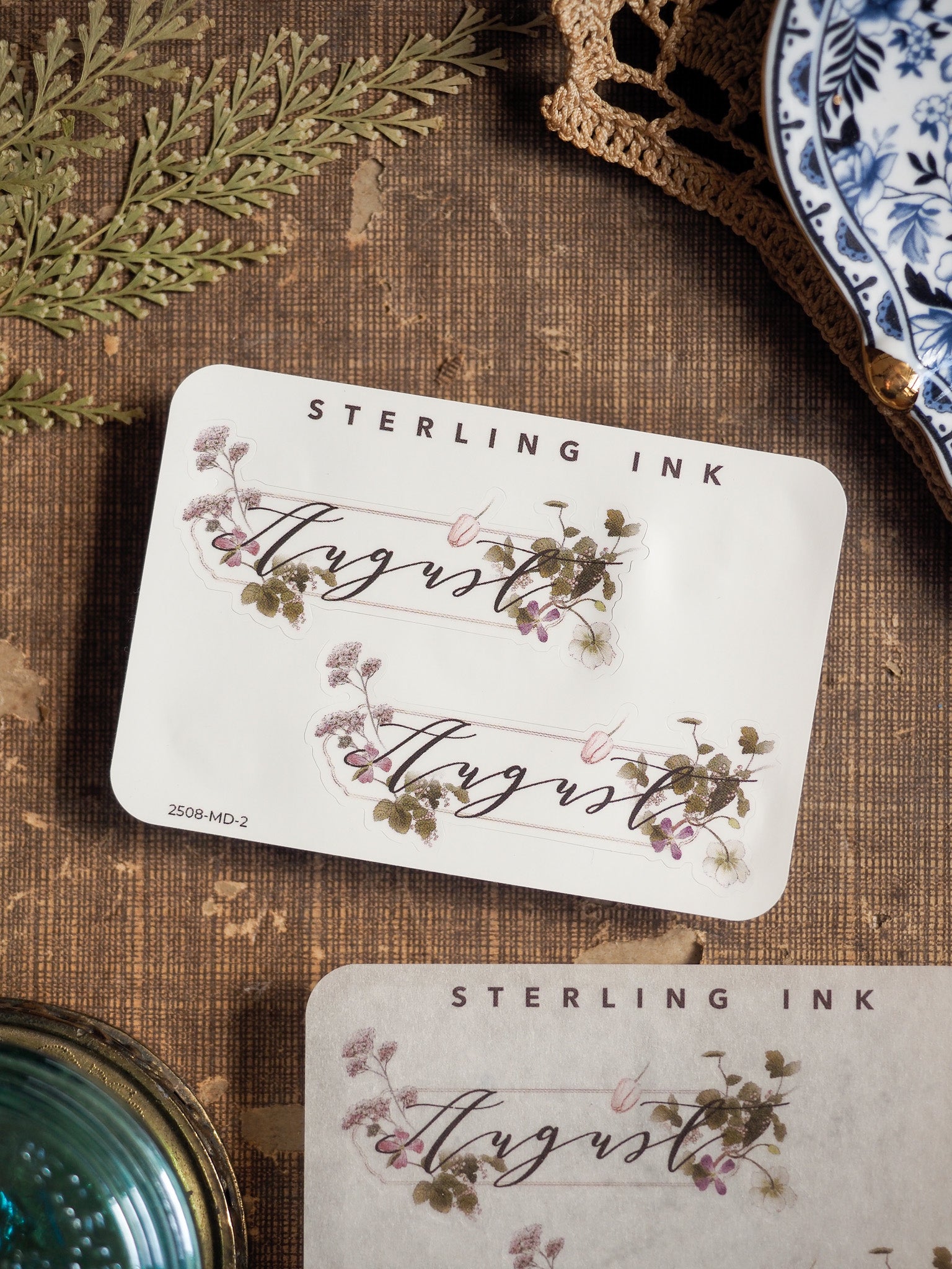 Delicate August month sticker sheet featuring natural watercolor wildflowers, leafy greenery, and the cursive month name for journal decorating.