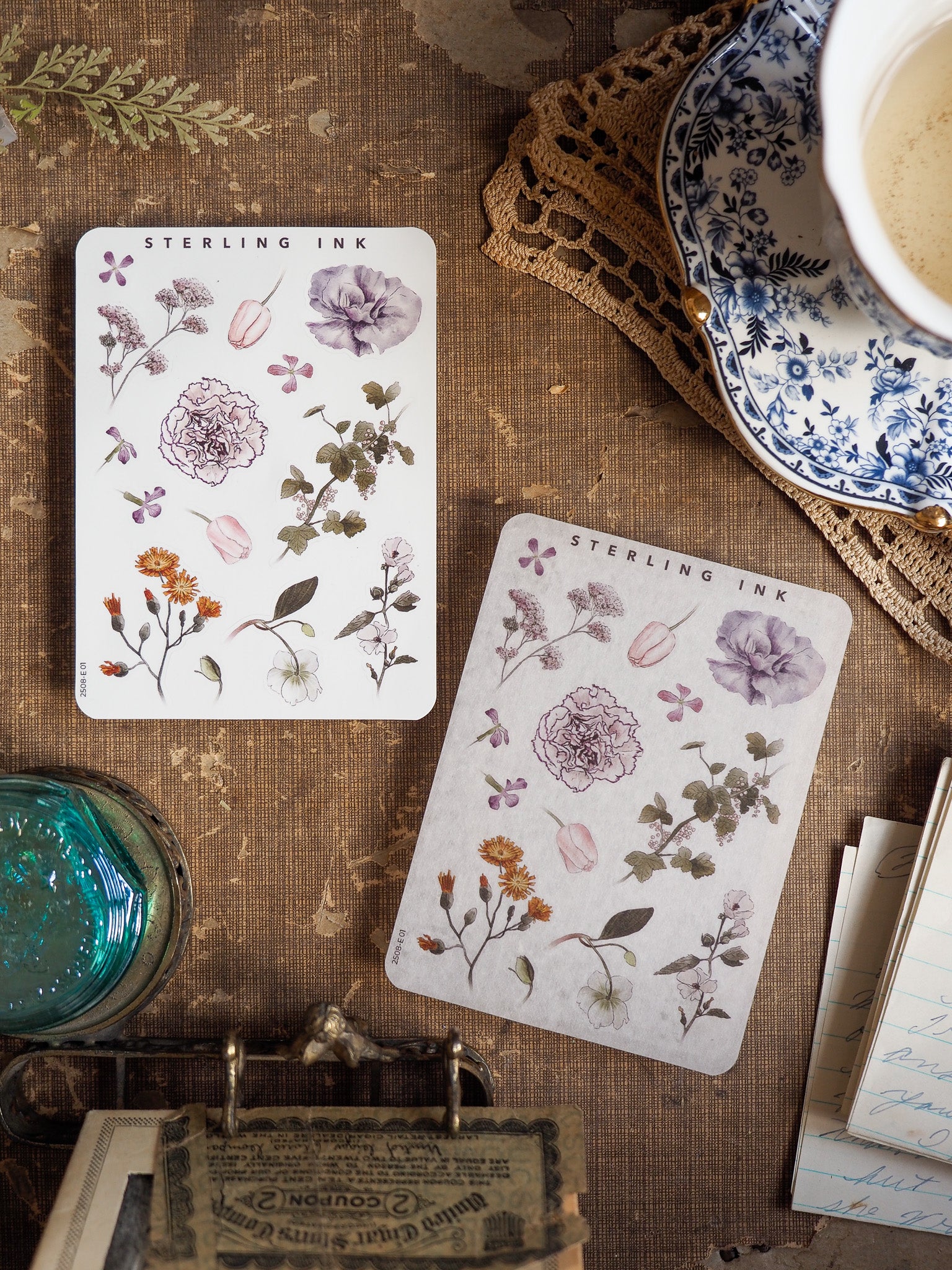 Delicate watercolor-style botanical elements adorn these sheets, featuring pastel purple, pink, and green floral clusters perfect for crafting.