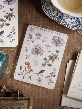 Botanical elements sticker sheet featuring watercolor illustrations of peonies, leaves, and assorted flowers in muted purple, sage green, and soft cream tones.