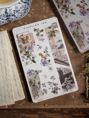 Elegant washi sticker strip featuring delicate watercolor florals in deep mauves and purples, framed by rustic, vintage ephemera and antique-style stamps.