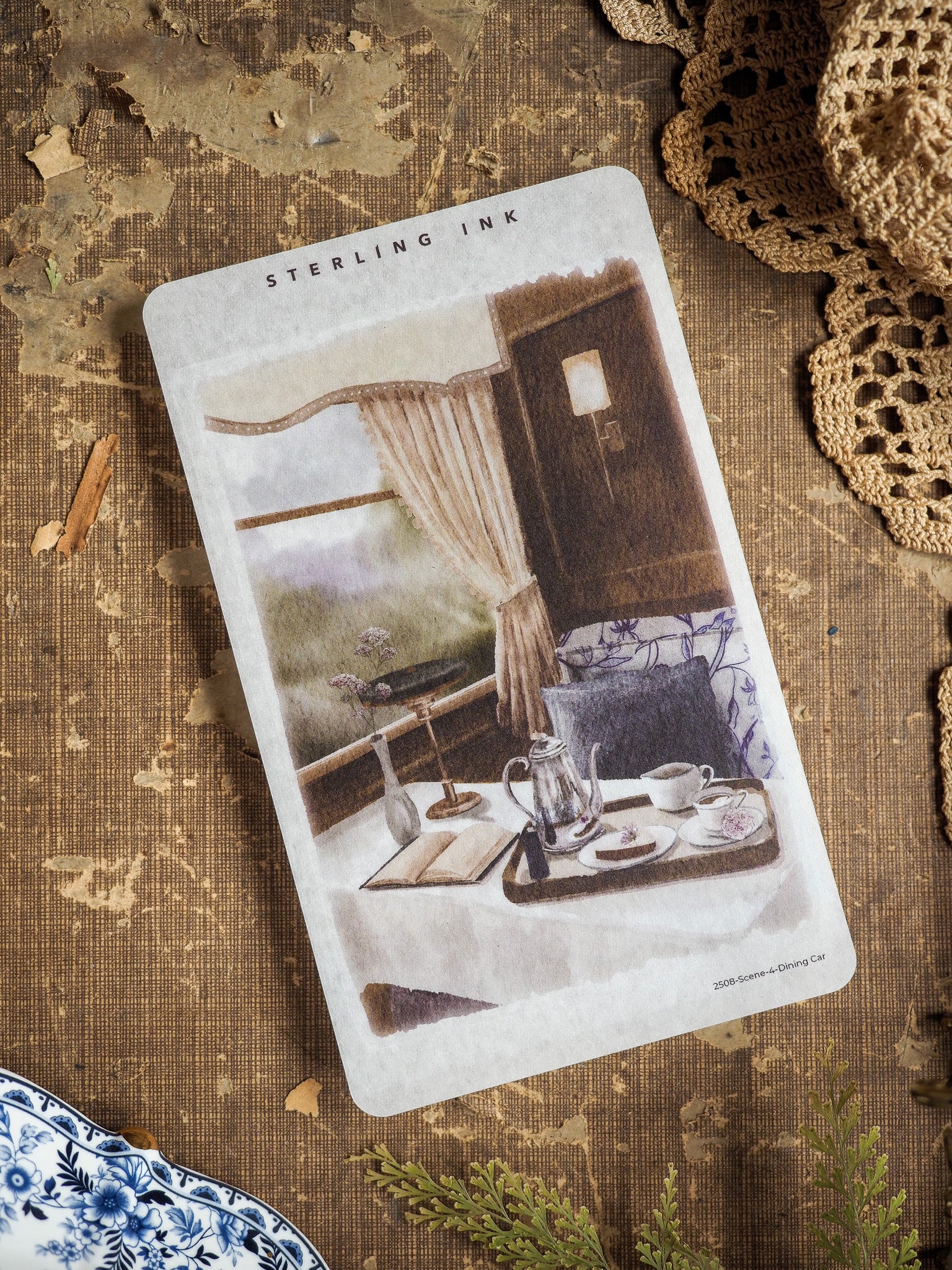 Vintage illustrated sticker of a cozy dining car scene, displaying a tea service, elegant table settings, and draped curtains.