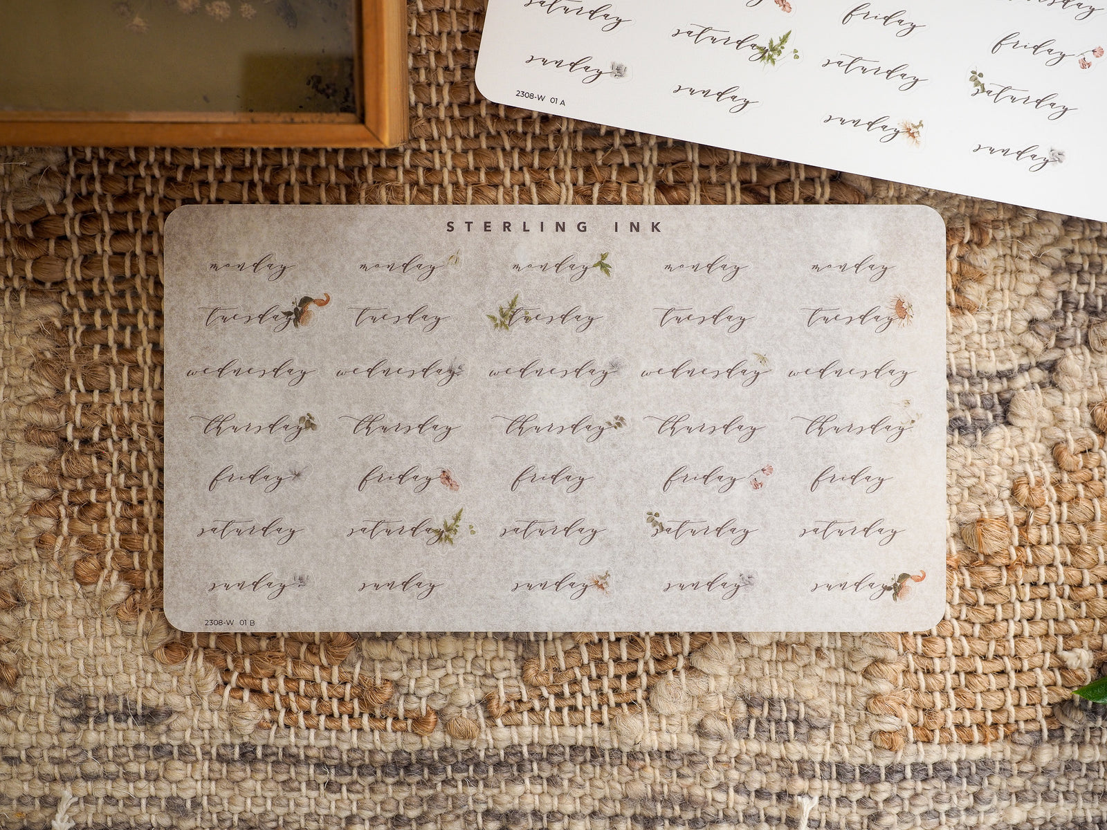 Decorative set of light beige stickers detailing the days of the week (Monday through Sunday) with a vintage, hand-lettered floral design perfect for August planning.