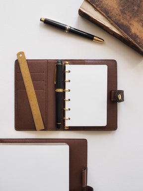 Deep brown, plain, ring-bound loose leaf inserts featuring crisp white pages, ideal for customizable journaling or academic note-taking.