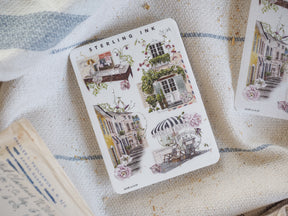 Sticker sheet titled "Sterling Ink" featuring an assortment of vintage watercolor illustrations of charming European architecture in soft blush pinks and creams.