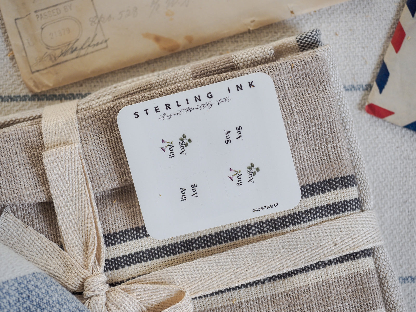 White, minimalist monthly tab card from Sterling Ink, featuring the repeating stylized text and decorative elements for the month of August.