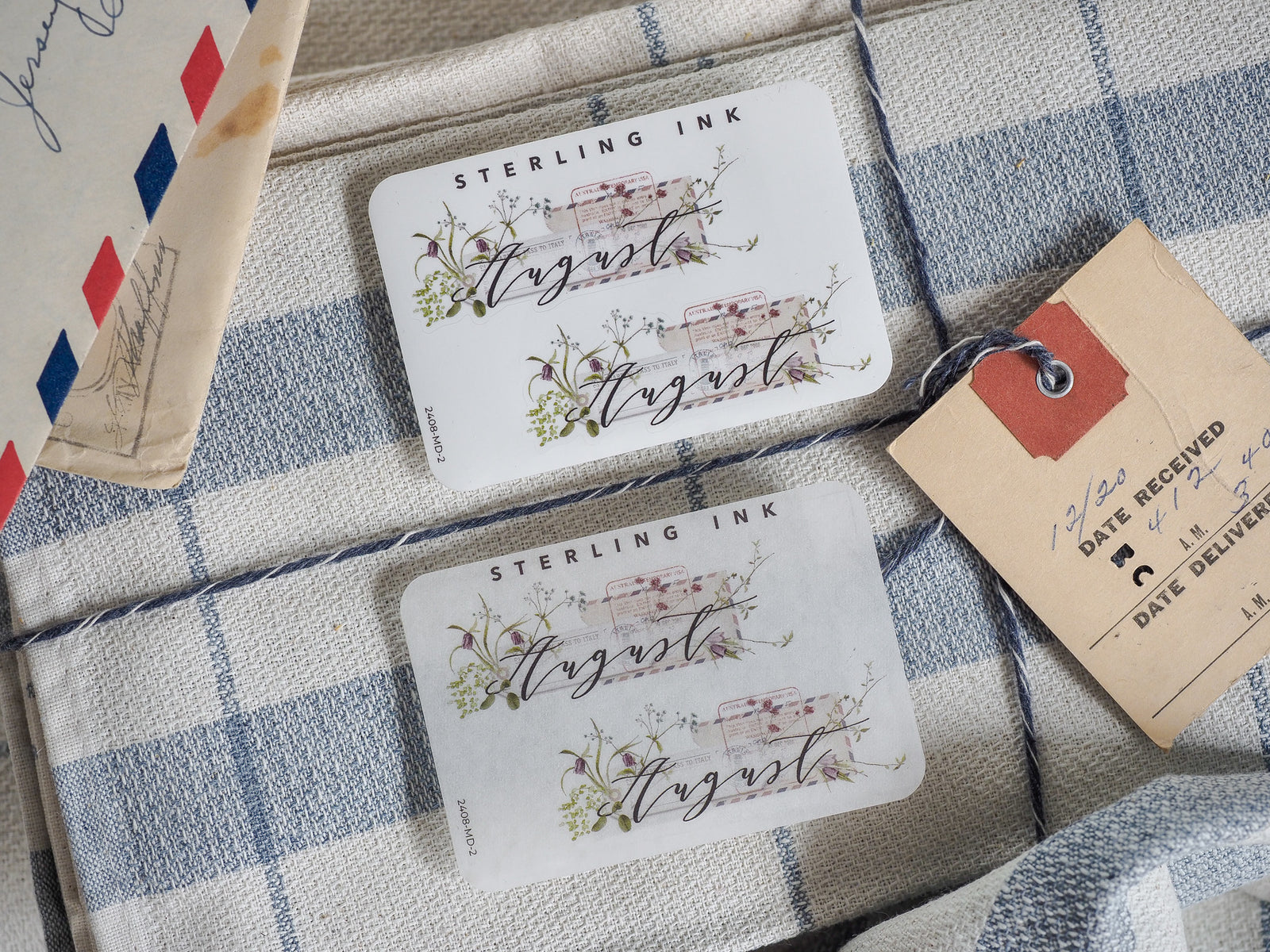 Decorative August month sticker featuring "STEARLING INK" and surrounded by delicate, muted watercolor florals and green botanical accents.