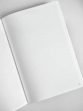Open A5 graph notebook displaying structured light gray grid paper, perfect for detailed journaling, planning, or technical note-taking.