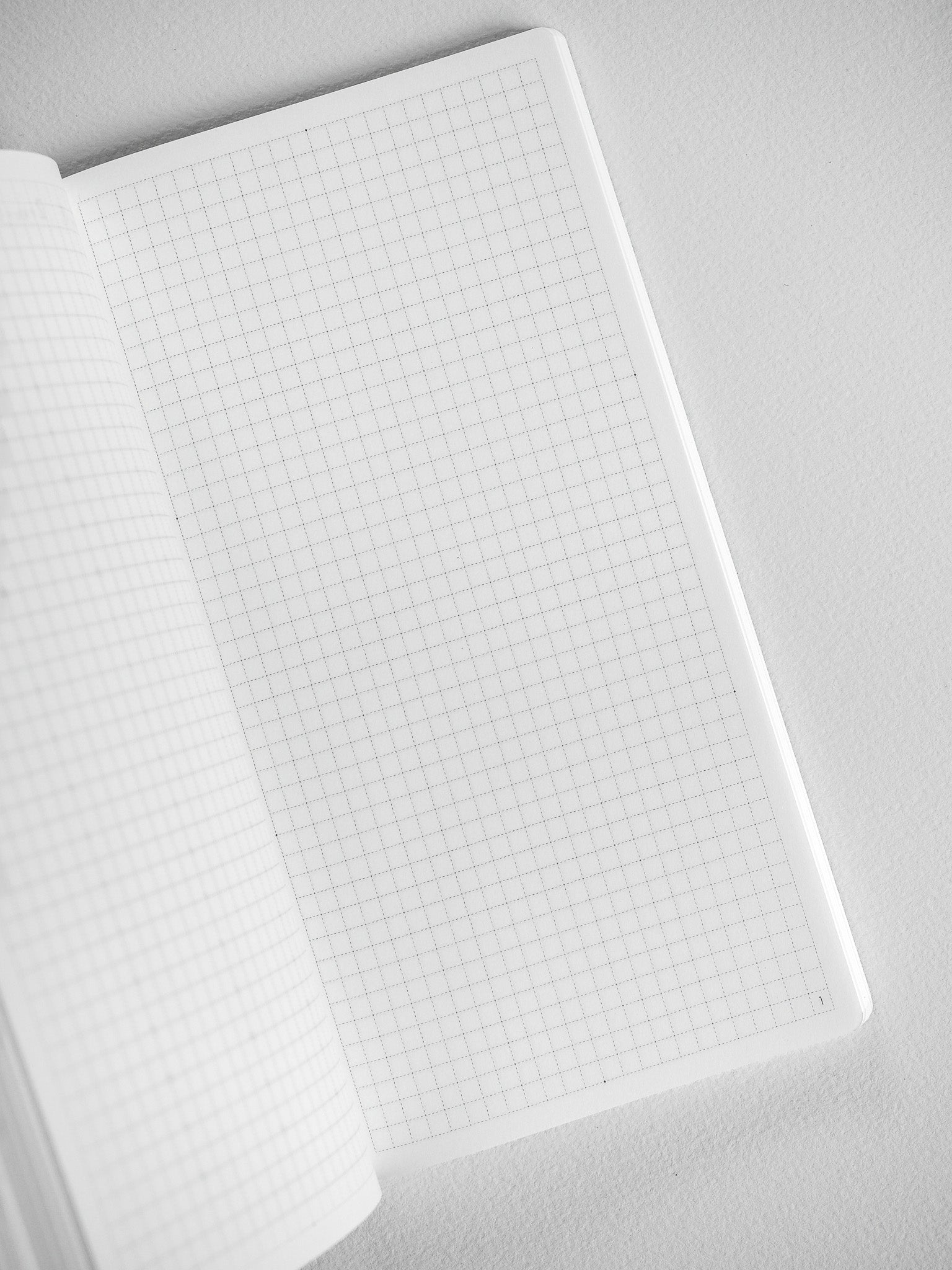 Open white notebook displaying precise, ruled graph paper grids across numerous pages, ideal for planning and study.