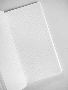 Open white notebook displaying precise, ruled graph paper grids across numerous pages, ideal for planning and study.