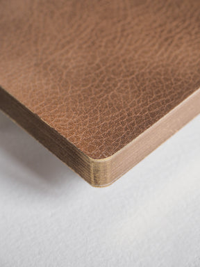 Structured A6 notebook featuring a deep, textured cocoa brown cover and substantial visible edges, ready for grid note-taking.