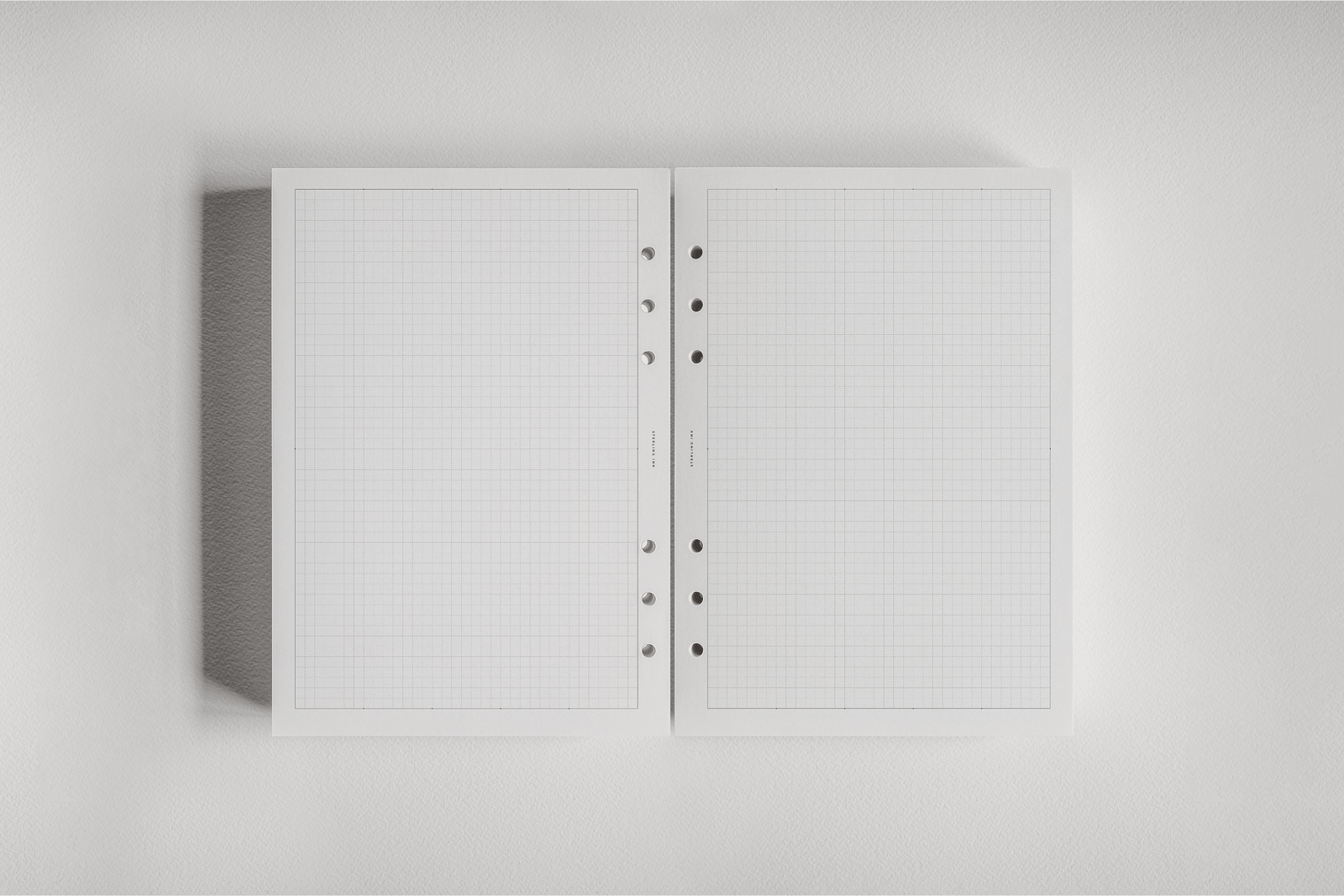 Graph-ruled white monthly planner inserts, bound for 2026 planning, featuring clean, organized grid lines perfect for tracking dates.