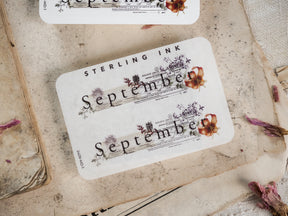 Retro "Sterling Ink" September month sticker with sepia tones, decorative Victorian typeface, and faded floral accents for journaling.