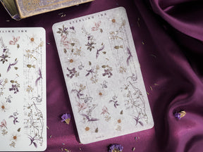 Vintage botanical sticker sheet featuring pressed purple and cream flowers mixed with delicate script and sepia-toned leaf illustrations for September crafting.